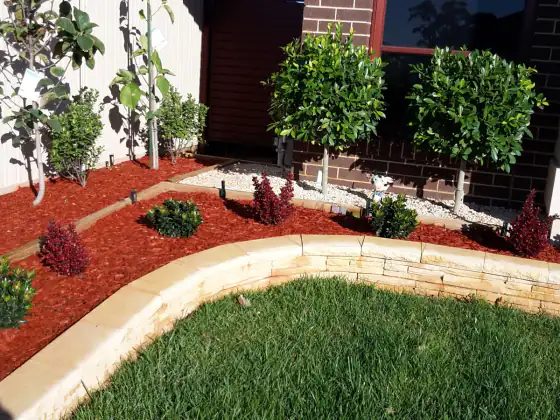 Mulched garden beds and lawn beside a brick home