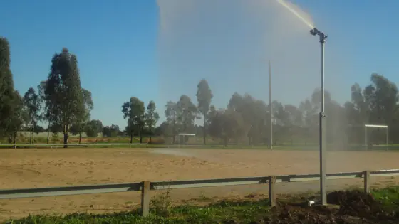 Irrigation gun sprinkler throwing a high arc of water across an open paddock