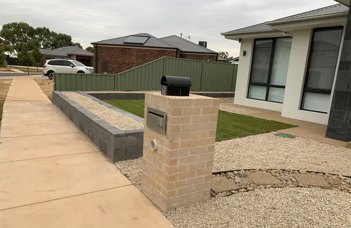 Brick letterbox, raised garden bed edging, lawn and pebble border at a new home
