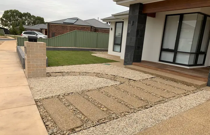 Exposed aggregate stepping pavers set in pebbles, leading to the porch of a new home