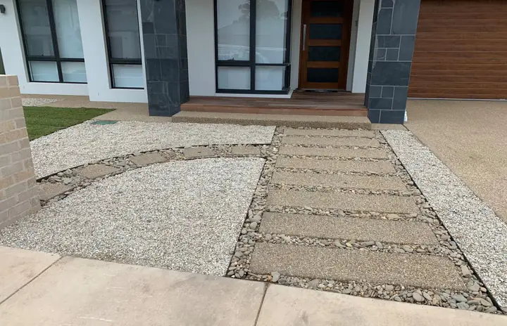 Curved pebble garden bed beside a pebble-set paved path to a front door