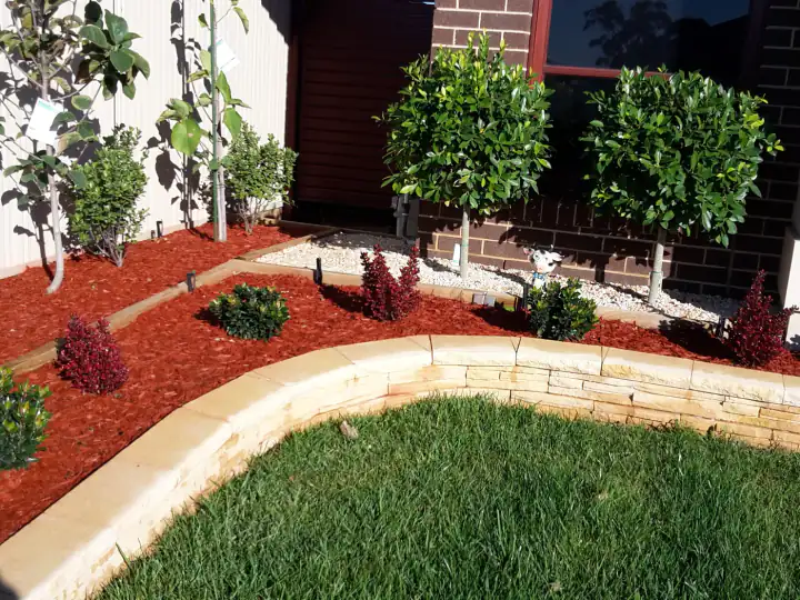 Mulched garden beds and micro-spray irrigation behind a low sandstone wall